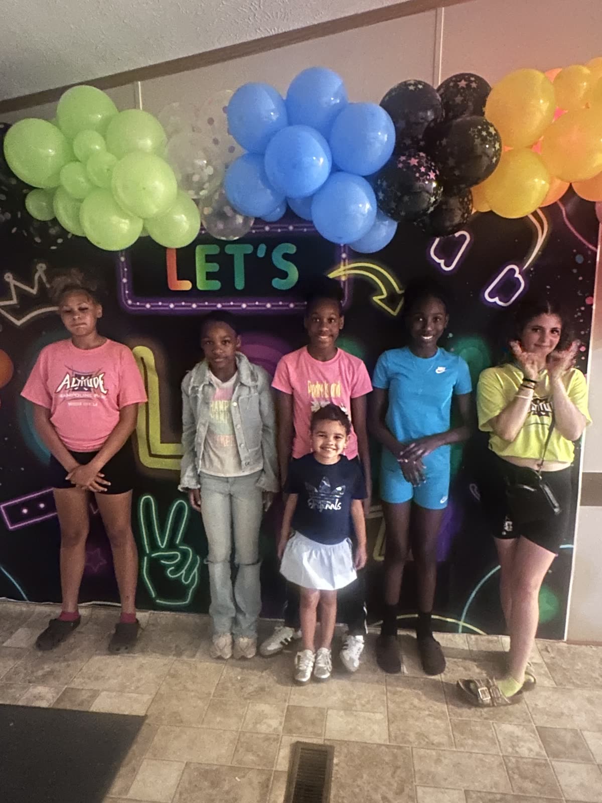 Young people posing in front of a colorful Neon Night backdrop